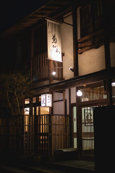 Façade du ryokan de nuit. Il s'agit d'une facade à l'aspect traditionnel, avec beaucoup de bois.