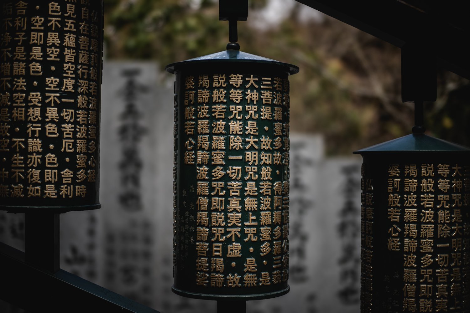 Des moulins à prière : de gros cylindres verts recouverts de symboles (probablement en chinois)