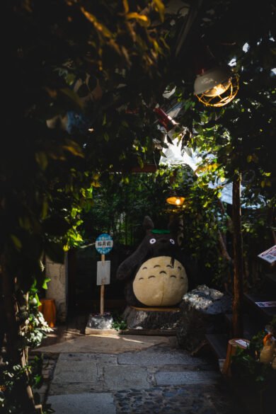 Un gros Totoro semble attendre un bus au milieu de plantes