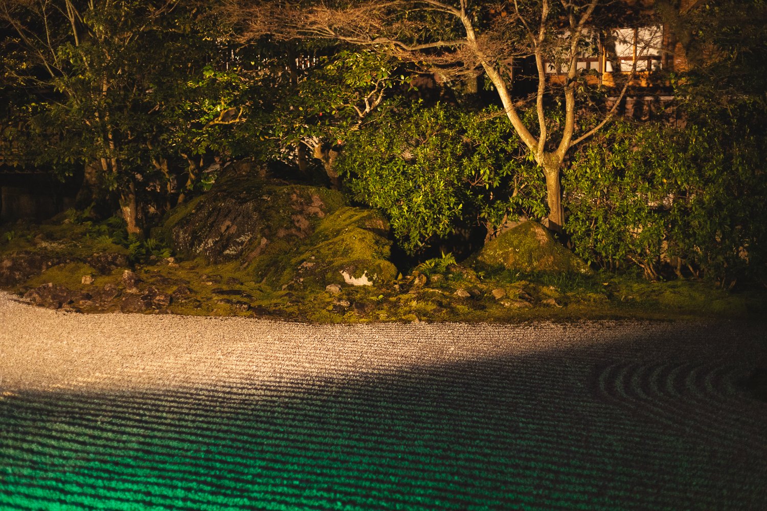 Le jardin zen du Entoku-in de nuit. Le jardin est éclairé par des lumières chaudes et des spots rasant verts qui font ressortir les sillons.